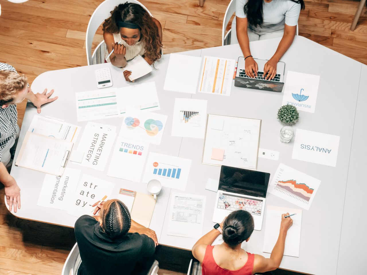 Overhead view of a marketing team surrounded by strategy, trends, and analysis documents
